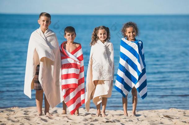 多种文化的孩子们采用富有色彩的毛巾st一d采用g在海滨一