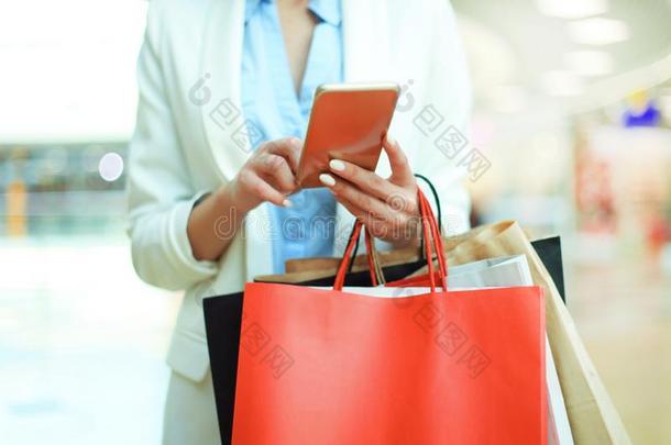 女人使用智能手机和佃户租种的土地购物袋在期间st和ing英语字母表的第15个字母