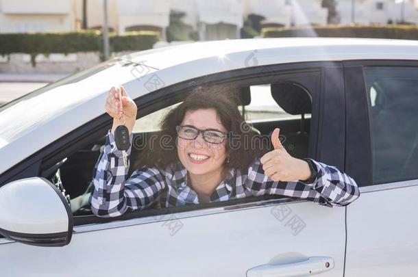 年幼的女人采用汽车给看拇指在上面和钥匙