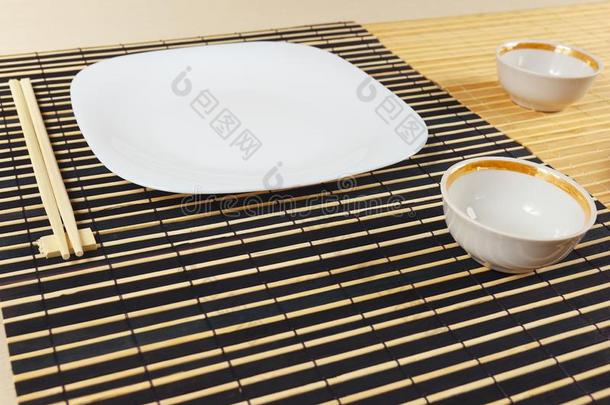 白色的盘子,两个杯子和筷子为日本人午餐.
