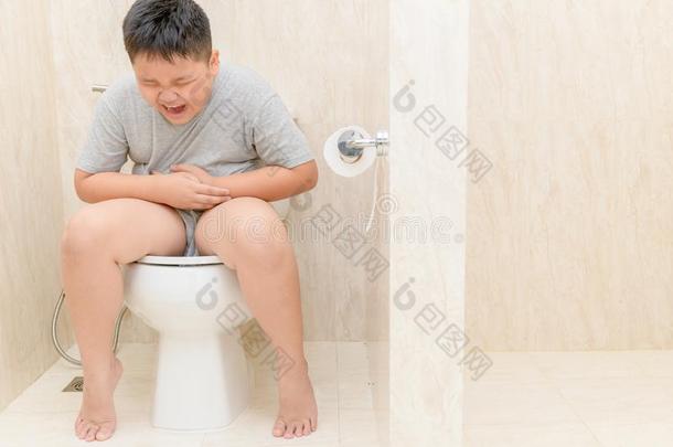 肥的男孩受痛苦胃和坐采用洗手间,