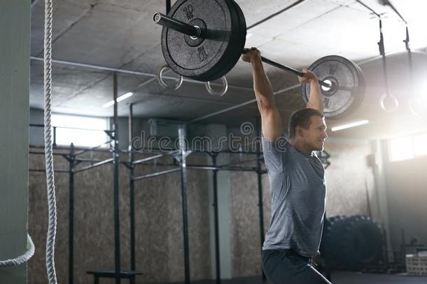 有关运动的男人举起<strong>杠铃</strong>行在锻炼健身房