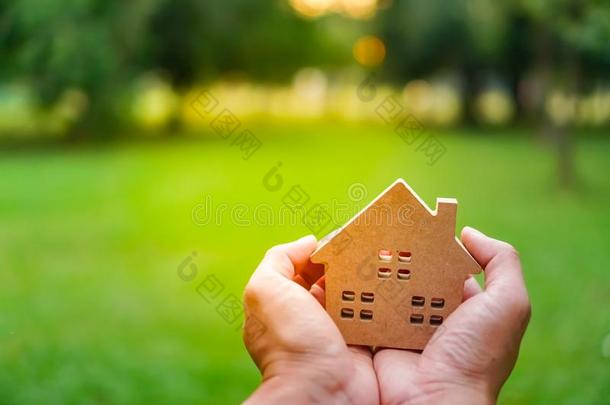 手拿住房屋模型向绿色的自然背景.