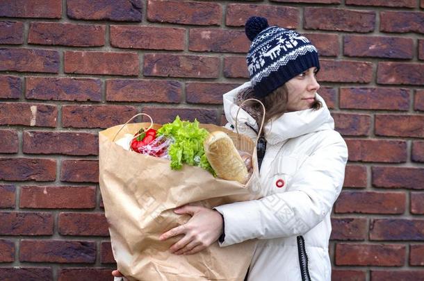 年幼的女人进行和纸袋关于蔬菜和食物从grocer食品商