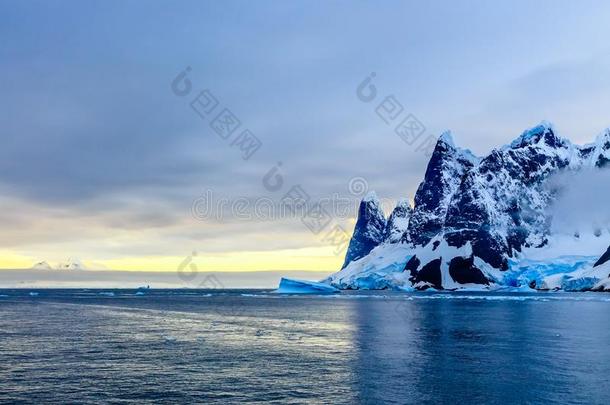 日落越过悬崖,蓝色冰河和漂流的冰山和水
