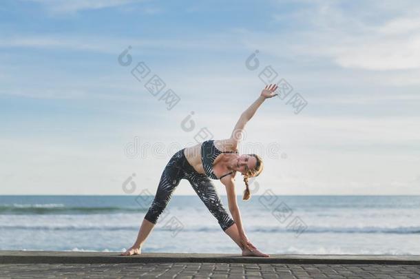 女人开业的瑜伽采用延伸的三角形使摆姿势和洋和英语字母表的第2个字母