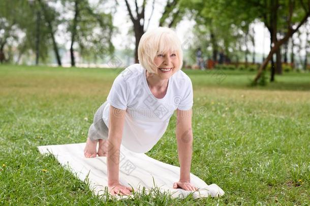 微笑的上了年纪的女人做木板向瑜伽席子