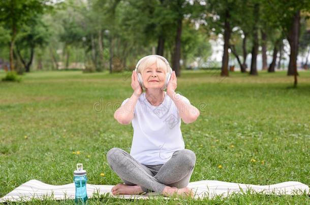 幸福的上了年纪的女人收听的音乐和耳机在期间席廷