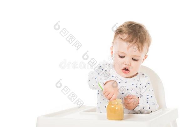 小的男孩<strong>吃</strong>浓汤从罐子和一次采用<strong>小孩吃</strong>饭时所用的高脚椅子