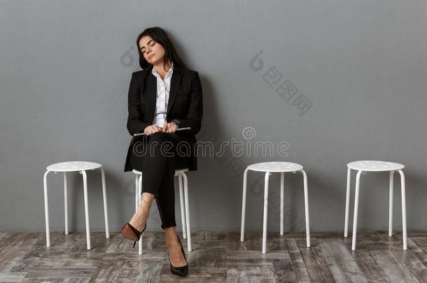 疲倦的女商人采用一套外衣和便携式电脑sleep采用g向椅子在期间