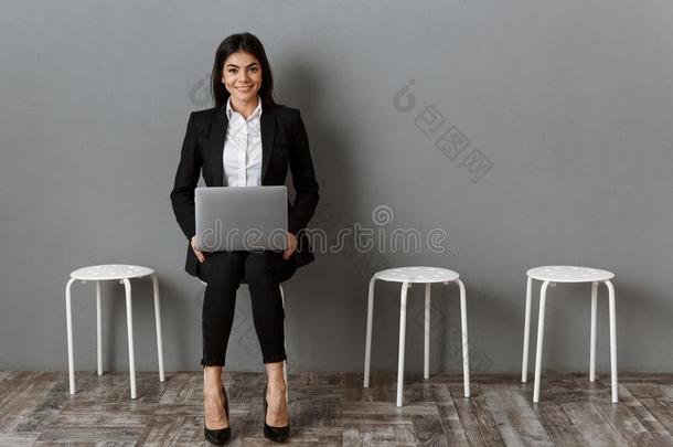 微笑的女商人采用一套外衣和便携式电脑wait采用g