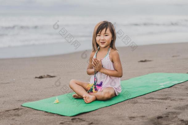 微笑的小的小孩<strong>开业</strong>的瑜伽采用莲花使摆姿势和合十礼
