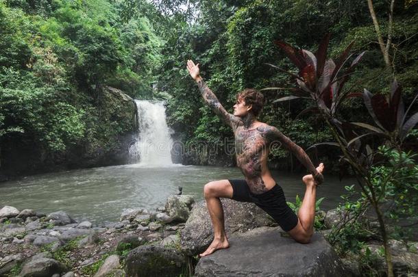 刺青男人开业的瑜伽向岩石和阿林-阿林瀑布
