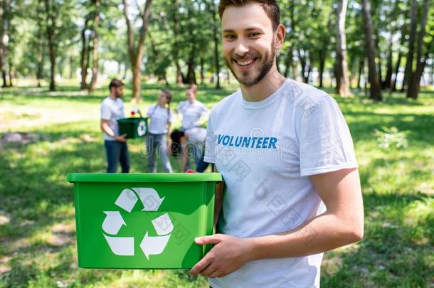 年幼的微笑的志愿者和绿色的再循环盒采用公园和France法国