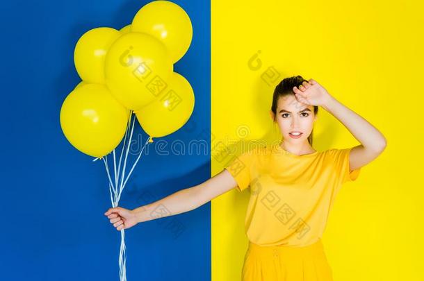 优美的黑头发的妇女女人佃户租种的土地束关于黄色的<strong>气球</strong>向蓝色