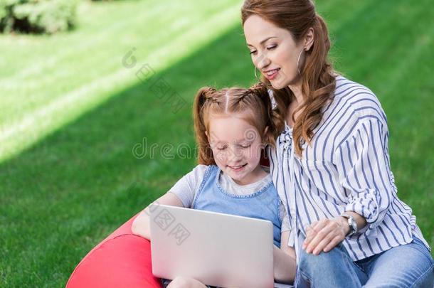 肖像关于母亲和女儿使用便携式电脑在期间静止的向波黑