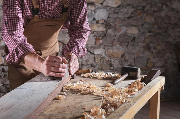 男人刮木板在期间它s它s向工作台