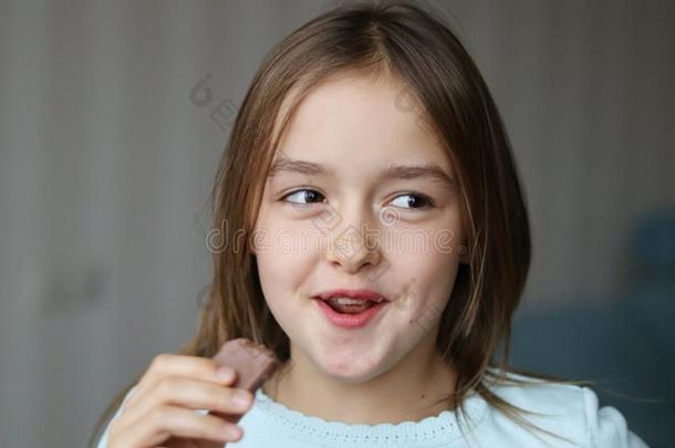 漂亮的幸福的微笑的小的女孩吃巧克力和有趣的面容