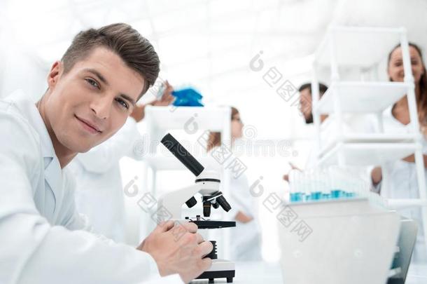 欢乐的实验室工人使用显微镜采用实验室