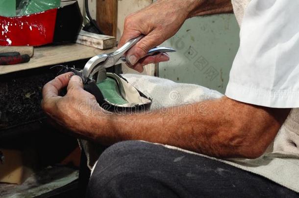 专业的鞋匠使用铁锤在期间制造新的鞋子