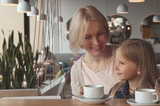 母亲和<strong>女儿</strong>给看他们的<strong>拇指</strong>在上面在指已提到的人咖啡馆