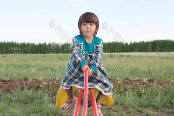 小的女孩摇摆向跷跷板在夏,有趣的面容幸福的小孩采用