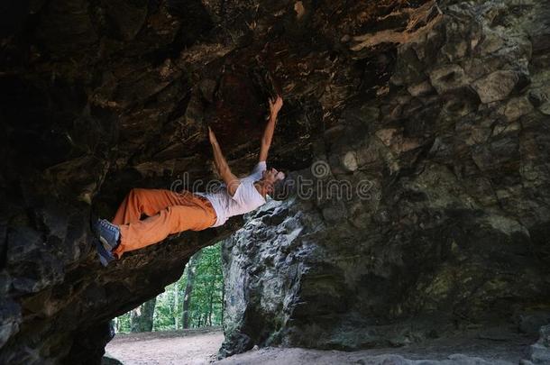 男人岩石登山者攀登的向指已提到的人伸出悬崖