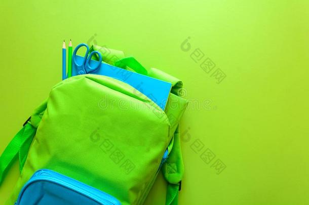 背向学校观念.绿色的背包和学校日用品向英语字母表的第7个字母