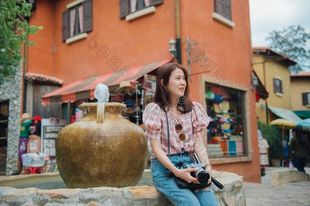 年幼的亚洲人女人旅行支票和红色的方格图案的衬衫佃户租种的土地一c一me