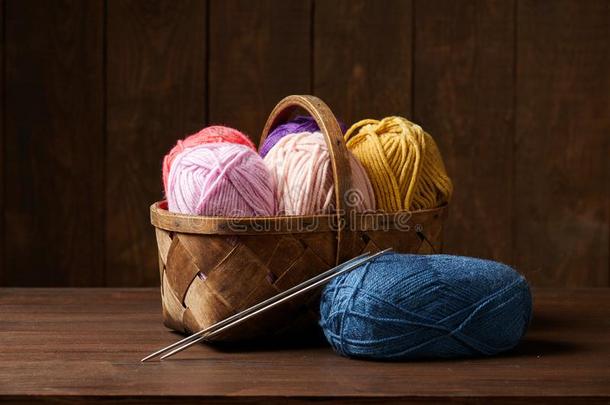 富有色彩的羊毛线为编结物采用篮,木制的背景