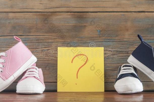 婴儿鞋子和纸张贴物和问题斑点向木制的后面