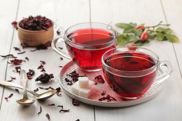 热的红色的卡卡德茶水采用玻璃杯子和干的干燥的茶水向一白色的木制的