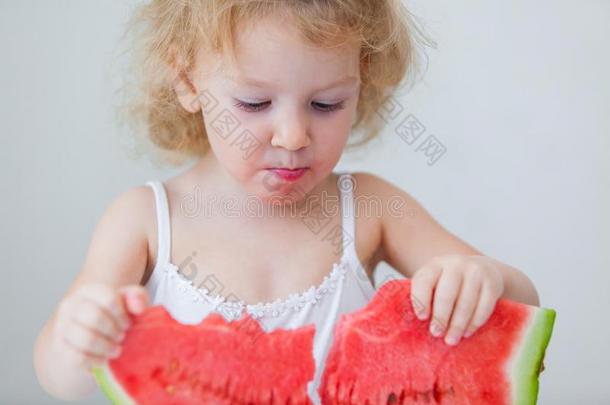 漂亮的小的婴儿女孩吃西瓜切成片向光后座