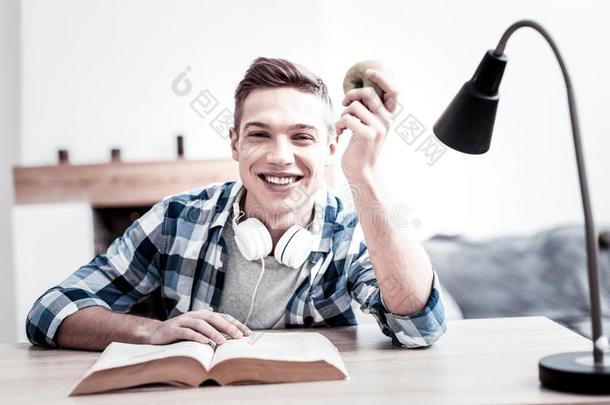 积极的学生微笑的在期间阅读和佃户租种的土地苹果