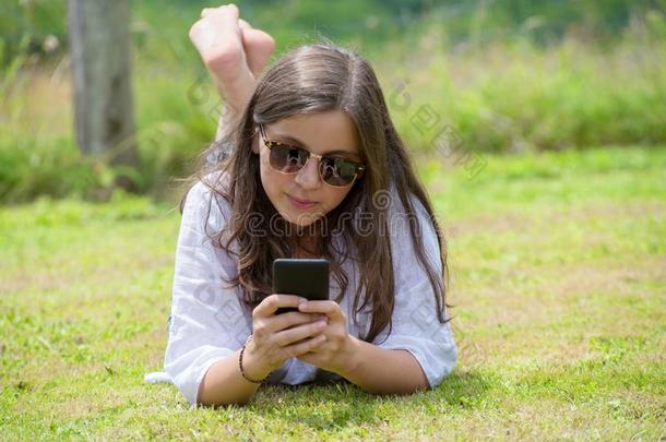 美丽的年幼的女孩和太阳镜是（be的三单形式使用指已提到的人智能手机