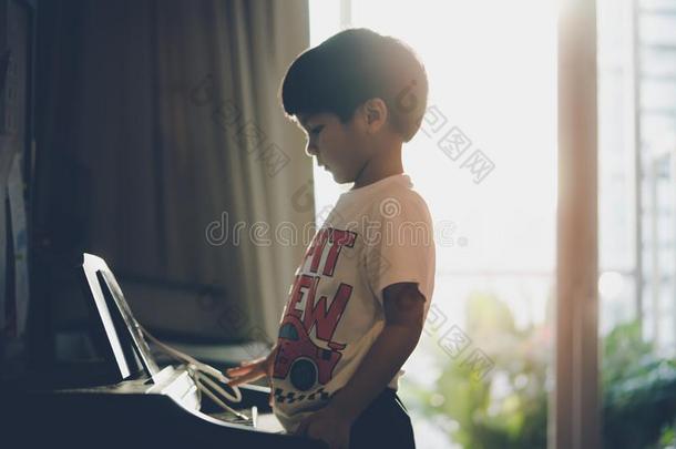 小的男孩演奏和钢琴和音乐碑在家