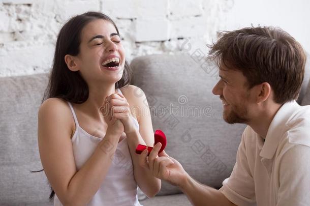 幸福的年幼的男人提议向他的女朋友一次向沙发