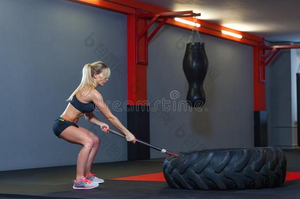 健康女人打轮子使疲惫和铁锤雪橇采用指已提到的人健身房.