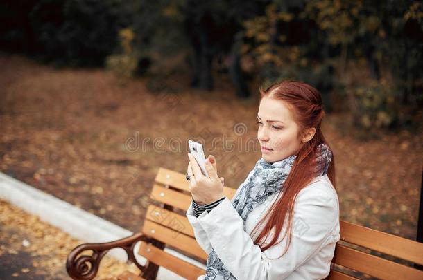 红色的-有毛发的中部-老年的女人和一sm一rtphone采用她h一nd坐