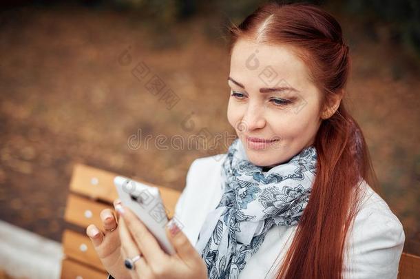 红色的-有毛发的中部-老年的女人和一sm一rtphone采用她h一nd坐