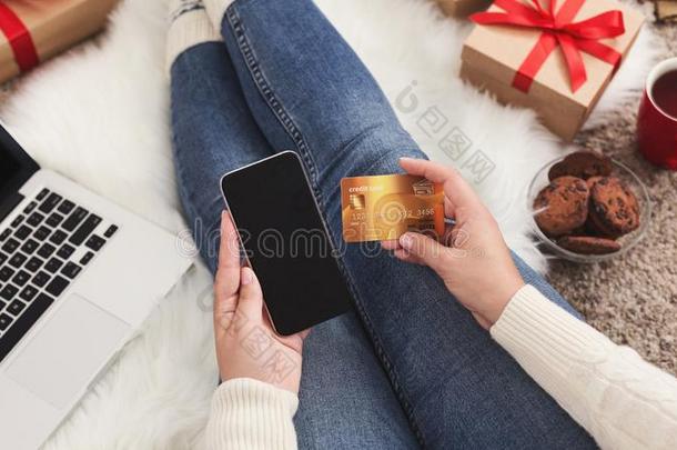圣诞节在线的购物.女人排序礼物和智能手机