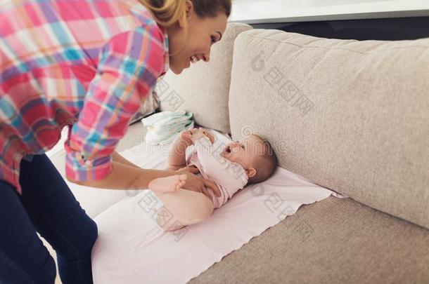 仔细的母亲<strong>襁褓</strong>微笑的婴儿向长沙发椅