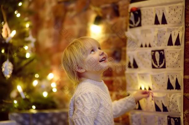 幸福的小的男孩拿甜的从出现日历向圣诞节英语字母表的第5个字母