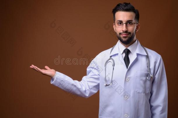 年幼的英俊的有胡须的伊朗的男人医生反对棕色的后台