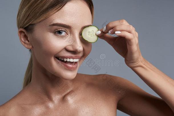 有趣的女人放置块关于黄瓜向她眼睛和微笑的
