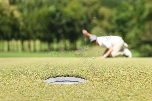男人高尔夫球手检查线条为放置高尔夫球球向绿色的草