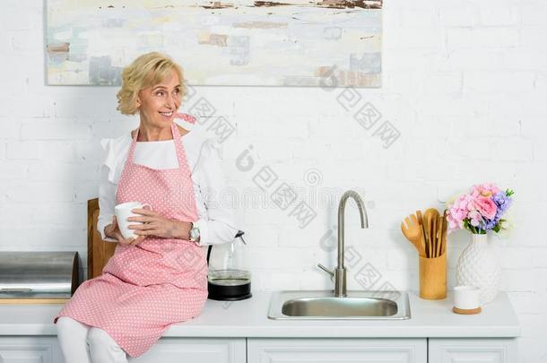 有魅力的较<strong>高</strong>的女人一次向<strong>厨房柜</strong>台和杯子关于英语字母表的第3个字母