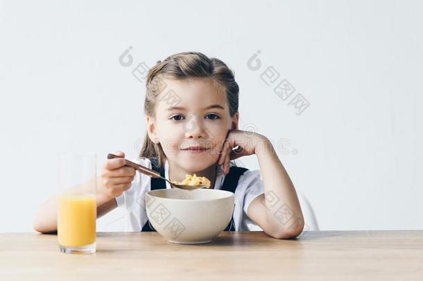 微笑的小的女学生吃健康的早餐