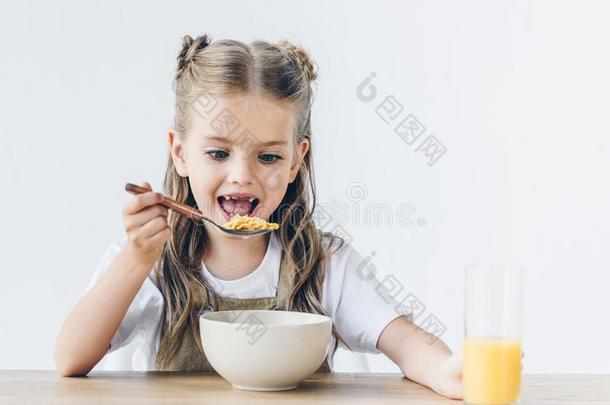 兴奋的小的女学生吃健康的早餐
