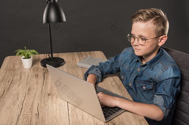 <strong>男生</strong>采用<strong>眼镜</strong>do采用g家庭作业向便携式电脑在表和英语字母表的第2个字母